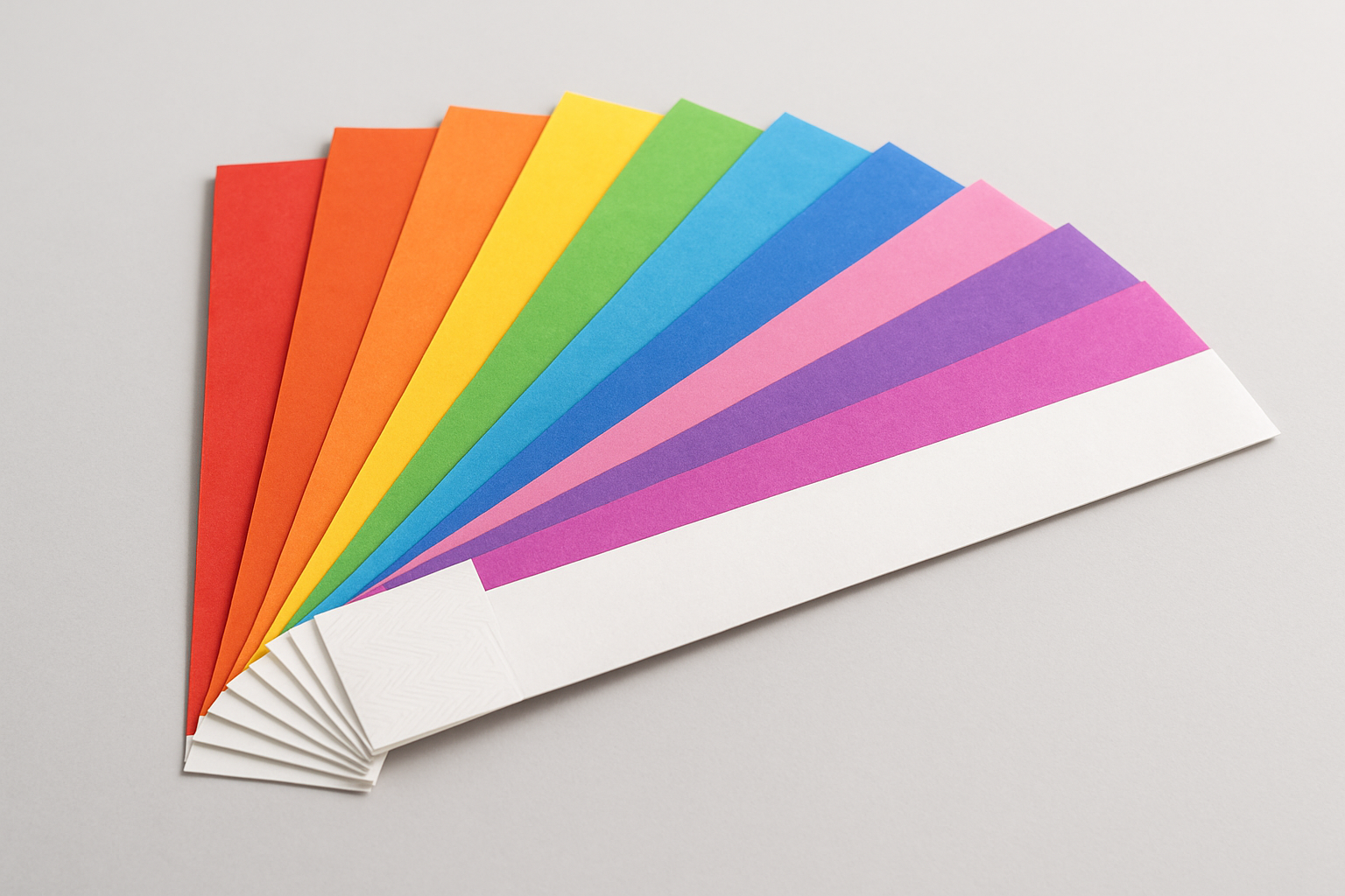 Blank paper wristbands in assorted colours fanned out showing adhesive tabs