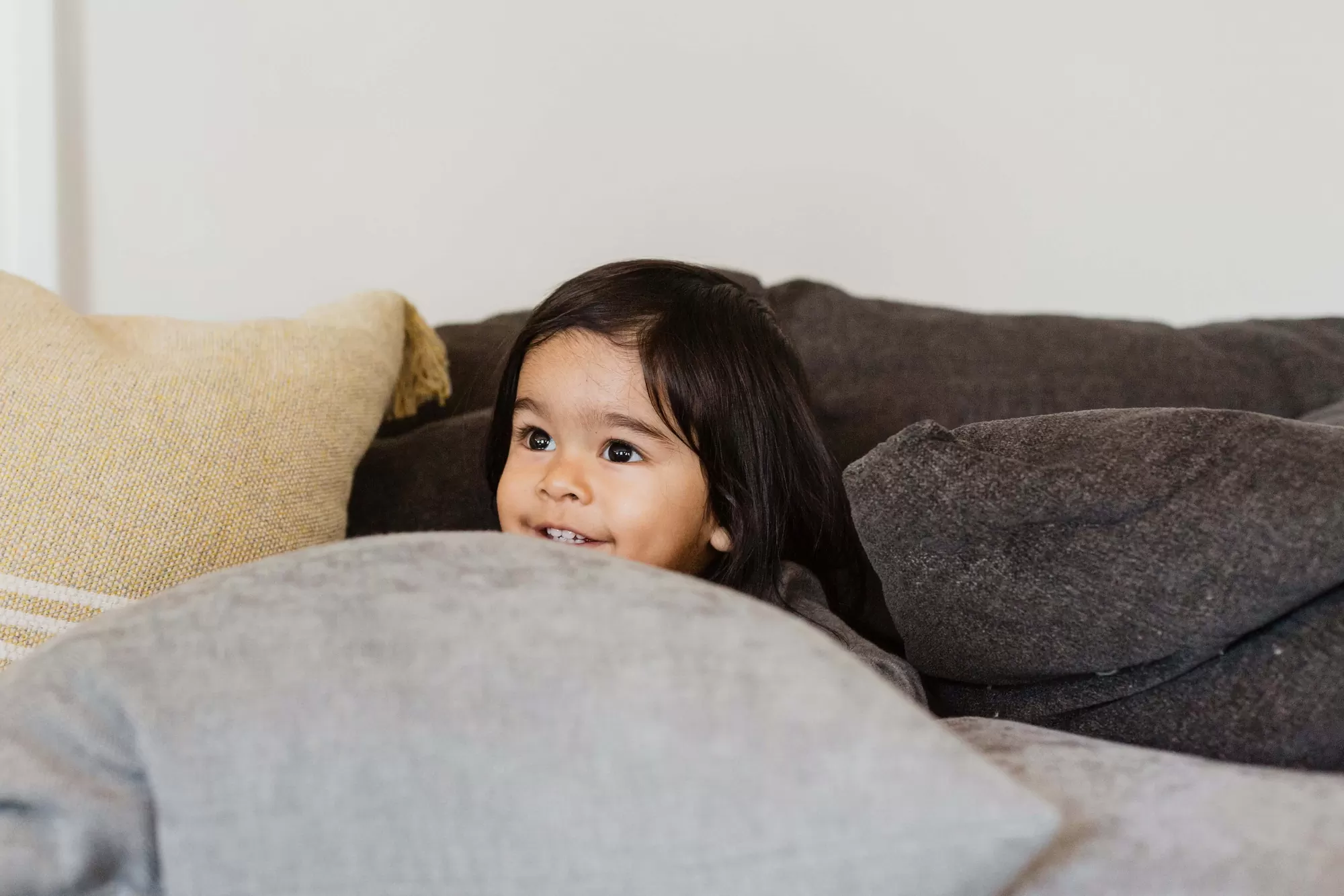Child peeking through pillows learning playfully — teaching children well