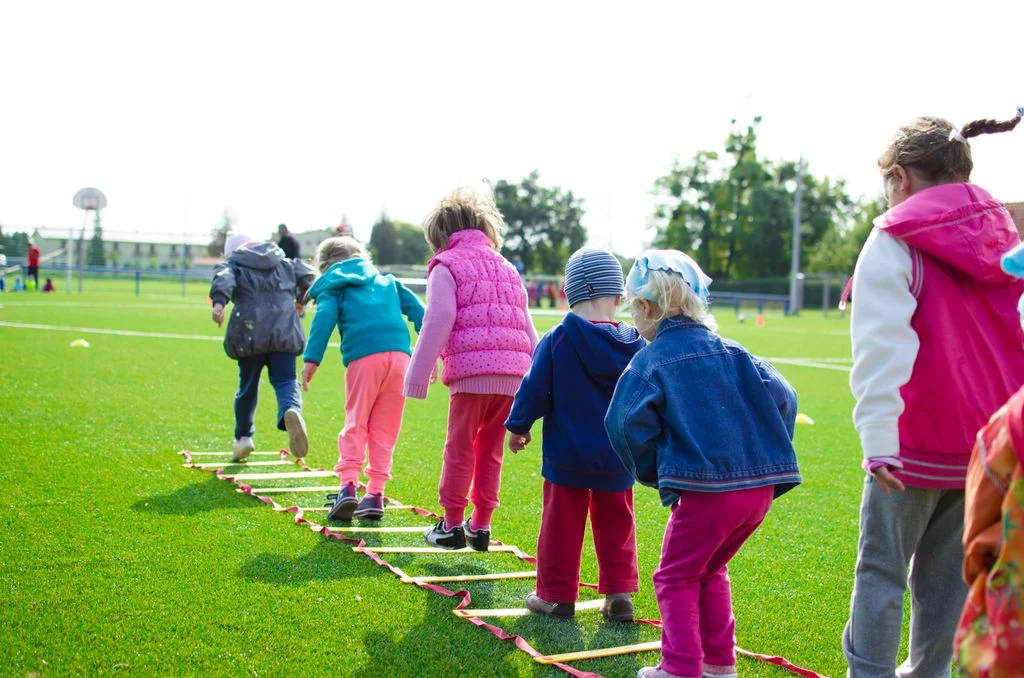 Children running through an agility ladder at a community sports club training session