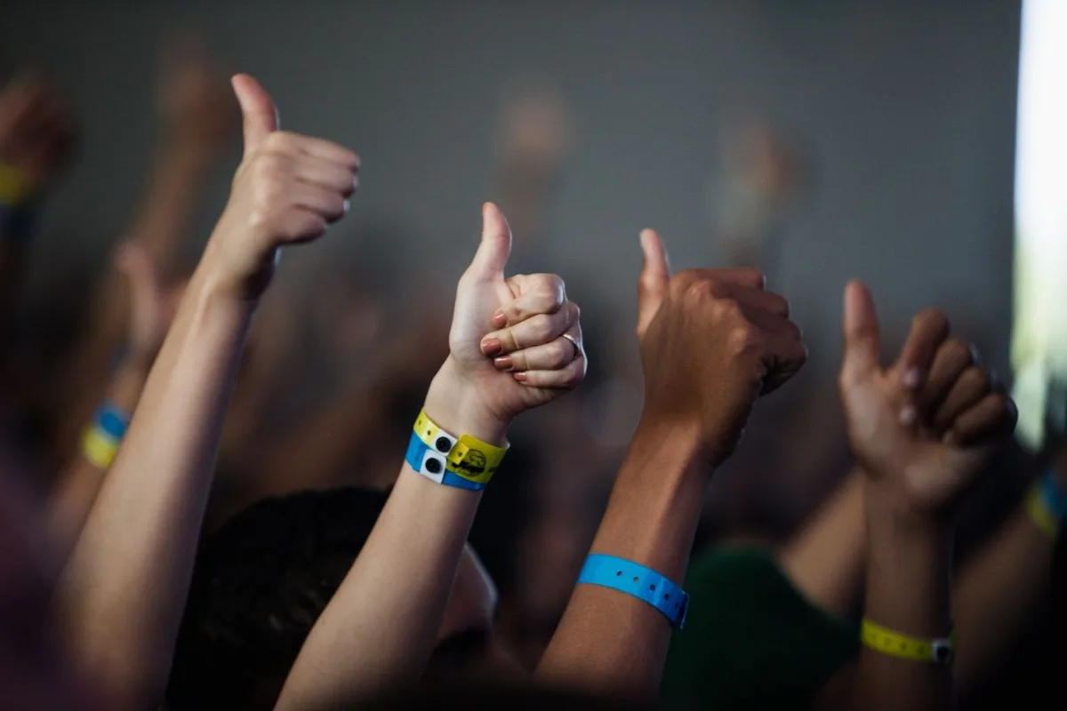 Hands raised at an event wearing coloured wristbands in different sizes on adult and younger wrists