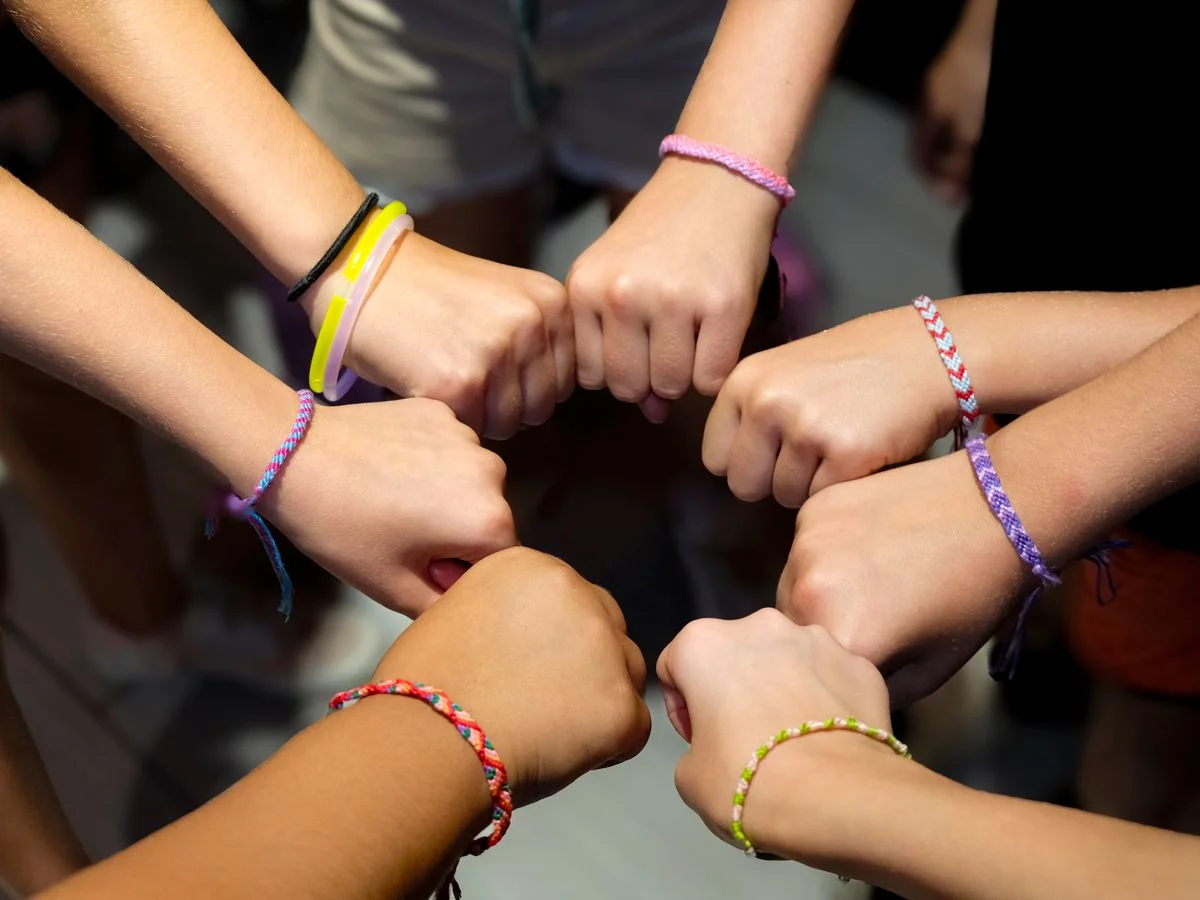 Circle of teenage hands wearing colourful friendship and fundraising bracelets