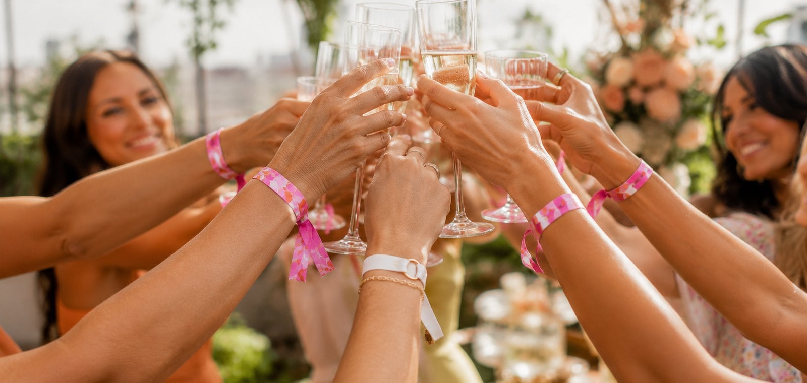 Hens party guests wearing matching custom team bride wristbands at a celebration