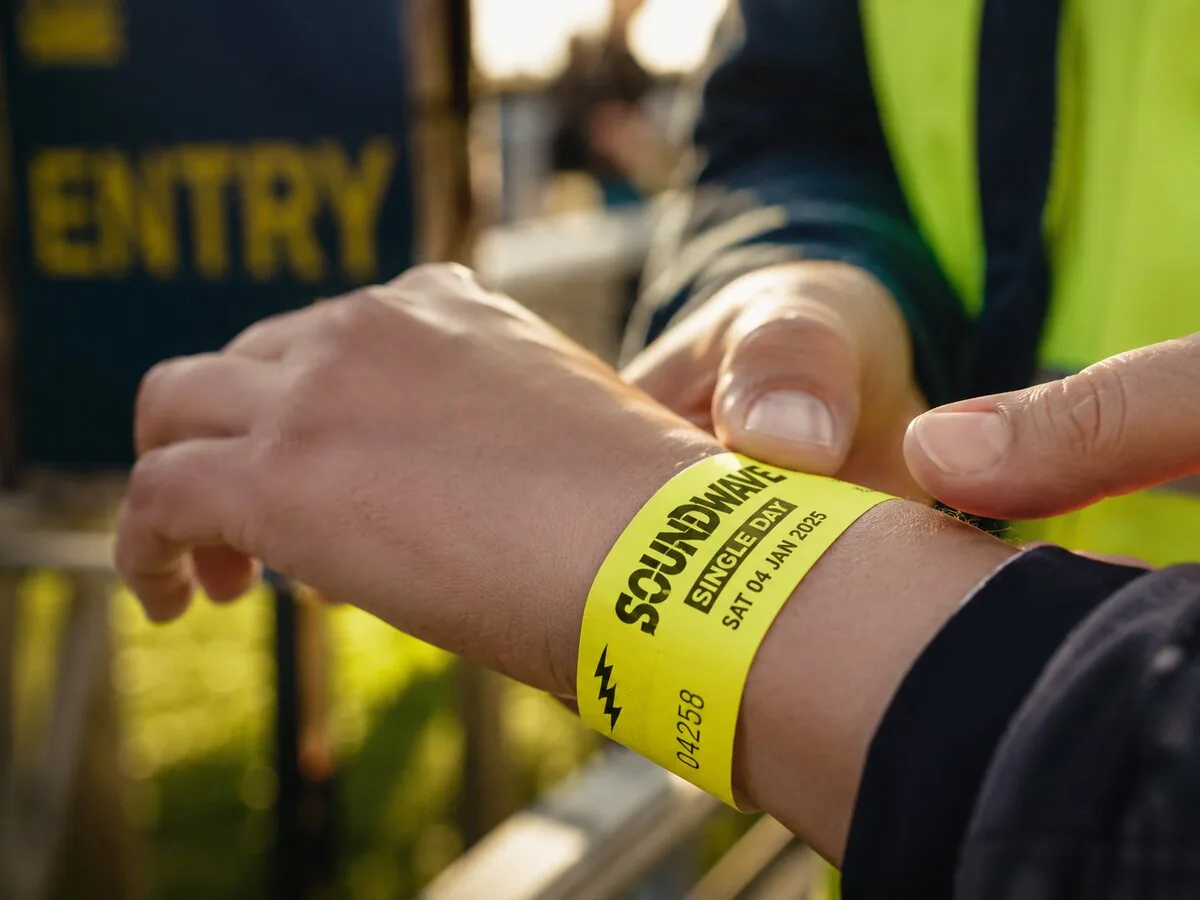 Macro of a Tyvek wristband being applied at a single-day event entry gate