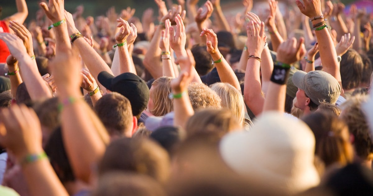Festival crowd wearing custom fabric music festival wristbands at golden hour