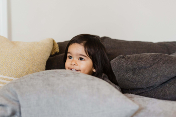 Child peeking through pillows learning playfully — teaching children well