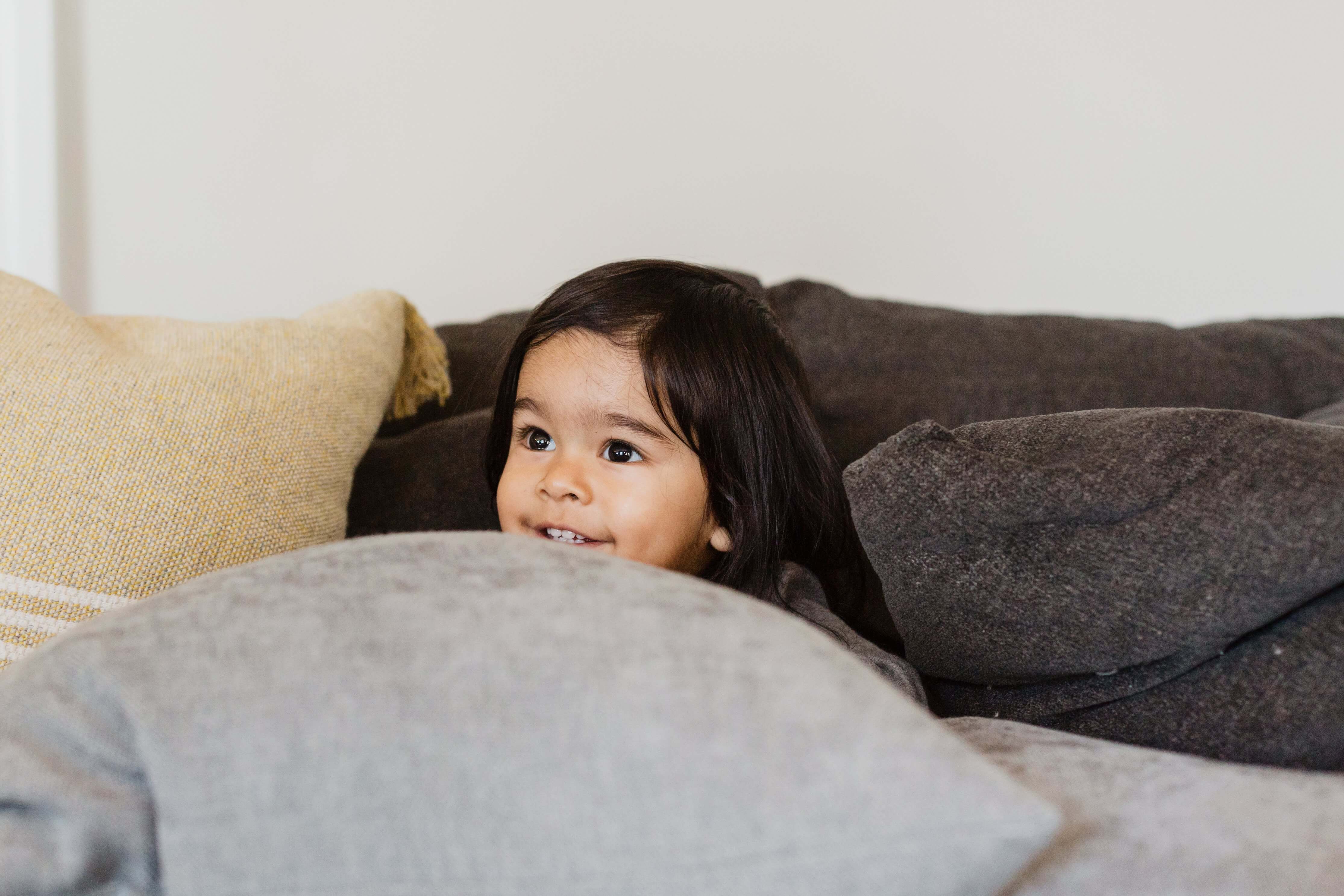 Child peeking through pillows learning playfully — teaching children well