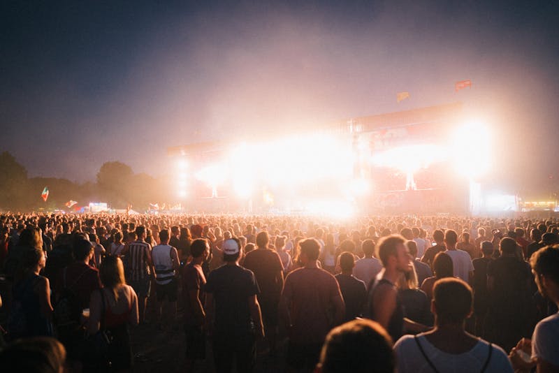 Large crowd enjoying a music festival with stage lights